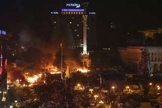 Manifestantes contra o governo se juntam perto do fogo em acampamento montado durante os confrontos com a polícia, em Kiev