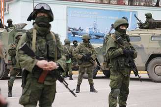 Soldados armados ao lado de veículos do exército russo esperam do lado de fora de um posto de guarda de fronteira na cidade de Balaclava, na Crimeia, em 1 de março