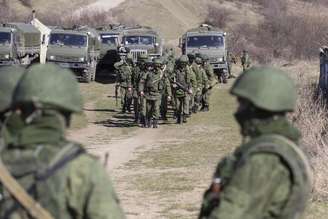 Tropas tidas como forças militares russas andam pelo lado de fora de uma base militare ucraniana, na vila de Perevalnoye, próxima a Simferopol. A Ucrânia afirmou que a Rússia está mobilizando veículos blindados de seu lado da fronteira próximo da região ucraniana da Crimeia desde que o presidente Vladimir Putin disse ter o direito de invadir seu vizinho, desencadeando um venda generalizada de ações russas. 03/03/2014