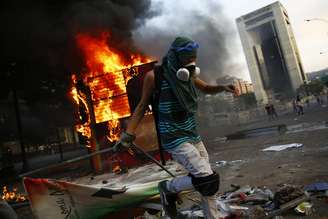 Opositor ao governo de Nicolás Maduro monta uma barricada junto aos restos de um quiosque na Praça Altamira, em Caracas, em 9 de março