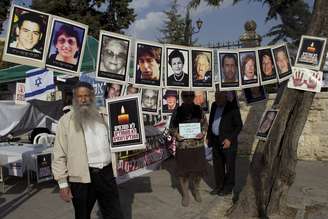 <p>Um homem israelense fica ao lado de retratos de israelenses que foram mortos por militantes palestinos, perto de uma barraca de protesto contra a libertação de prisioneiros palestinos, em frente à residência do primeiro-ministro em Jerusalém, em 1 de abril</p>