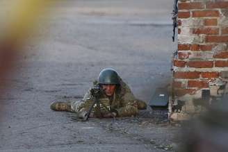 <p>Um soldado ucraniano aponta sua arma contra os manifestantes pró-Rússia que se reuniram em frente de uma base aérea ucraniana em Kramatorsk, no leste da Ucrânia. Pró-russos que ocupavam um aeroporto da cidade foram alvo de uma operação de tropas ucranianas nesta terça-feira</p>