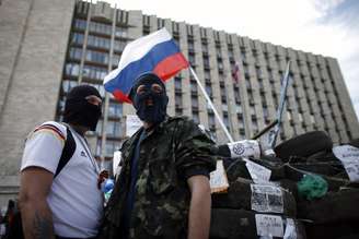 <p>Manifestantes pró-Rússia montam guarda perto de barricada montada em frente a um edifício do governo na cidade de Donetsk, em 23 de abril</p>