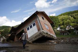 <p>Uma mulher caminha perto de uma casa inclinada por inundações na vila de Krupanj, a oeste de Belgrado, em 19de  maio</p>