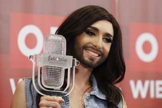 <p>Conhita Wurst posa ao lado do seu troféu, recebido no concurso Eurovision. A "mulher barbada" foi acusada de ser a culpada sobre as enchentes na região dos Bálcãs</p>