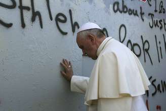 <p>Papa Francisco toca o muro que separa Israel da Cisjordânia a caminho da missa na Praça da Manjedoura, perto da Igreja da Natividade, em Belém</p>