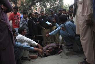 <p>Polícia coleta evidências do crime próximo ao corpo de Farzana Iqbal, que morreu apedrejada pela própria família, próximo à Alta Corte de Lahore, em 27 de maio</p>