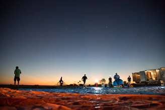 Equipe do Loon prepara o lançamento durante o amanhecer, enquanto ciclistas curiosos param para olhar