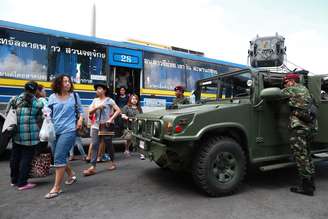 <p>Soldados tailandeses montam guarda enquanto passageiros de um ônibus caminham próximo ao Monumento da Vitória em Bangcoc, em 8 de junho</p>