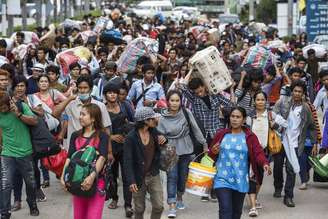 <p>Cambojanos carregam seus pertences enquanto caminham para atravessar a fronteira em Aranyaprathet, em Sa Kaew, Tailândia, em 15 de junho</p>