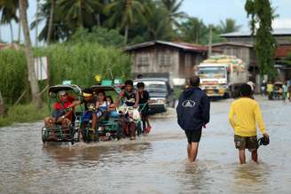 <p>Moradores cruzam uma estrada inundada em Mindanao, nas Filipinas, em 15 de julho</p>