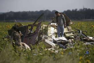 Um rebelde separatista pró-Rússia protege o local da queda do avião da Malaysia Airlines enquanto monitores europeus e investigadores malaios inspecionam a área, na região de Donetsk, no leste da Ucrânia, nesta terça-feira. 22/07/2014