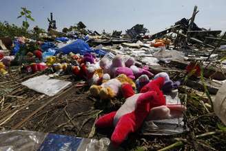 <p>Restos do avião da Malaysia Airlines são vistos ao lado de brinquedos, deixados no local por residentes do local da queda, na Ucrânia</p>