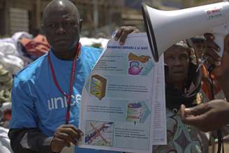 <p>Um trabalhador UNICEF segura um cartaz com informações para evitar o ebola em Conacri, capital da Guiné</p><p> </p>