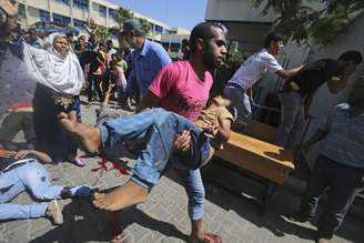 <p>Um palestino carrega um menino ferido seguindo o que testemunhas disseram que foi um ataque aéreo israelense em uma escola das Nações Unidas-run, onde os palestinos deslocados refugiar, em Rafah, no sul da Faixa de Gaza</p>