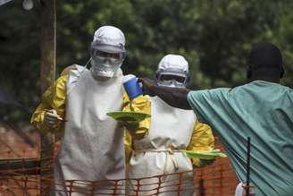 <p>Médicos do grupo Médicos Sem Fronteiras preparam a alimentação dos pacientes mantidos em uma área de isolamento de tratamento contra o Ebola, em Kailahun, Serra Leoa, em julho</p>