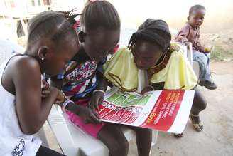 <p>Meninas olham para um cartaz, distribuído pela Unicef, tendo informações e ilustrações das melhores práticas que ajudam a prevenir a propagação do Ebola, na cidade de Voinjama, em Lofa County, na Libéria</p>