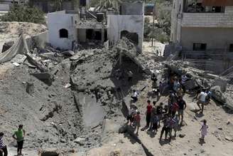 <p>Palestinos observam uma cratera aberta após uma casa ser atingida por um ataque aéreo israelense no norte da Faixa de Gaza, em 22 de agosto</p>