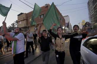 <p>Palestinos brandem bandeiras nacionais durante celebração do acordo de cessar-fogo entre Israel e Hamas na principal rua da Cidade de Gaza</p>