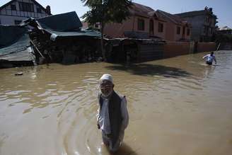 Cidadãos da Caxemira caminham em meio a água e casas danificadas, em uma rua inundada, em Srinagar , em 14 de setembro