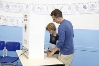 Luciano Huck votou no Rio de Janeiro neste domingo (5) e acabou desrespeitando a lei ao deixar seu filho votar na urna eletrônica