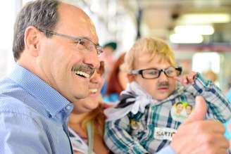 <p>Candidato José Ivo Sartori faz foto com criança com "bigode" em vagão do Trensurb, em 9 de junho</p>