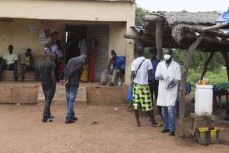<p>Agente da saúde aguarda para medir temperatura de pessoas que entram no Mali vindas da Guiné, na região de fronteira de Kouremale, no início de outubro</p>