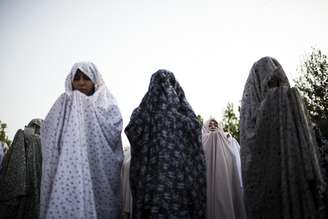 <p>Com os corpos completamente cobertos, mulheres muçulmanas iranianas fazem suas orações em Teerã, em 29 de julho</p>