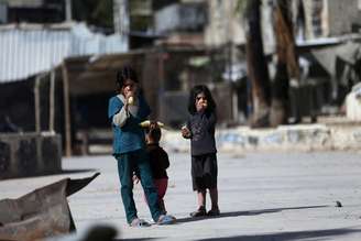 Crianças sírias comem milho em uma rua em Douma, no leste da al-Ghouta, perto de Damasco; o EI fechou escolas ao leste do país nesta sexta