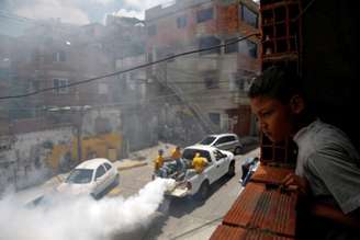 Menino observa trabalhadores aplicando remédio contra mosquito da dengue em rua de Caracas. 22/09/2014