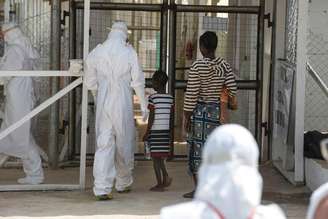 Agente da saúde acompanha novos pacientes de Ebola num centro de tratamento nos arredores de Freetown, em Serra Leoa, em dezembro. 22/12/2014
