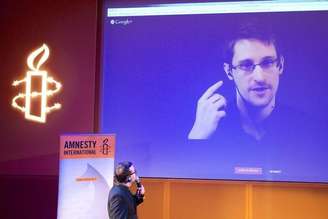 <p>Ex-prestador de serviço da NSA Edward Snowden, que está em Moscou, é visto em telão durante videoconferência realizada pela Anistia Internacional, em 10 de dezembro</p>