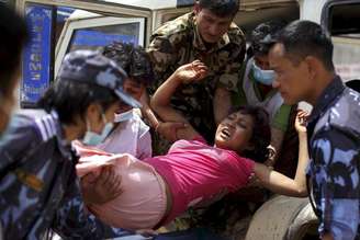 Militares e voluntários carregam uma mulher ferida ao hospital Dhading, após o terremoto de sábado, em Dhading Besi, no Nepal, nesta segunda-feira. 27/04/2015