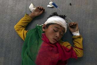 Menino machucado dormindo do lado de fora de um hospital lotado no Nepal (27/04/2015)