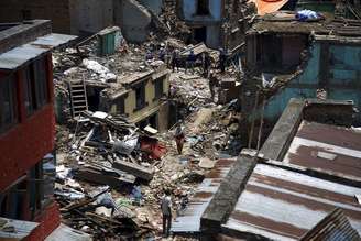 Pessoas caminham em meio a destroços após novo terremoto em Sankhu, no Nepal. 12/5/2015.