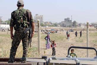 Membro das Unidades de Proteção Popular curdas (YPG) observando moradores, na Síria.  23/06/2015