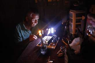 Homem repara um aparelho eletrônico em meio a corte de luz em San Cristobal, na Venezuela