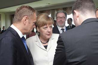 Presidente do Conselho Europeu, Donald Tusk (esq.) em conversa com a chanceler alemã Angela Merkel