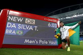 Thiago Braz posa ao lado do placar com seu recorde olímpico de 6,03m