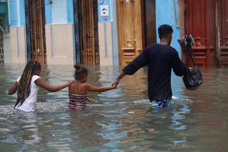 Um homem e suas duas filhas passam por rua alagada, após passagem do furacão Irma em Havana, Cuba 10/09/2017 REUTERS/Stringer