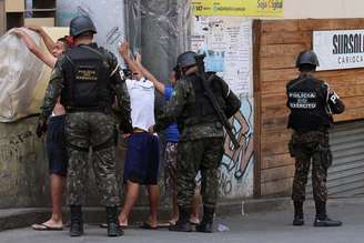 Policiais do Exército revistam pessoas em via da favela da Rocinha, no Rio de Janeiro