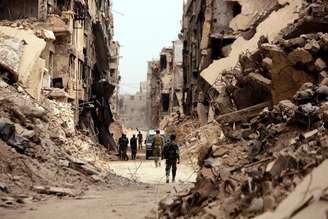 Soldados passam por prédios destruídos em Damasco, na Síria