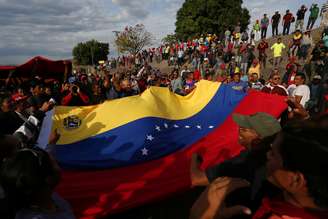 Manifestantes seguram bandeira da Venezuela durante protesto favorável ao governo na fronteira entre o país e o Brasil
24/02/2019 REUTERS/Bruno Kelly