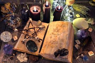 Antigo livro de bruxa com pentagrama, velas pretas, cristais e objetos rituais 