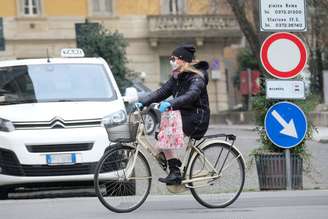 Mulher anda de bicicleta com máscara de proteção em Cremona, norte da Itália, devido à epidemia de coronavírus