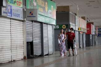 Pessoas, uma delas com máscara de proteção, caminham em frente a lojas fechadas em Brasília por causa de propagação do coronavírus 
20/03/2020
REUTERS/Ueslei Marcelino