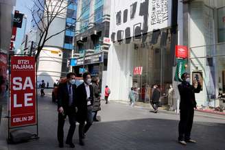 Homens usando máscaras de proteção caminham em distrito comercial em Seul
23/03/2020 REUTERS/Heo Ran 