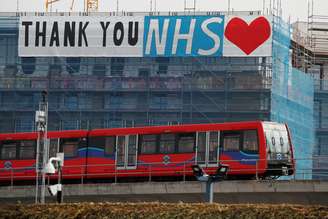 A Docklands Light Railway train is seen passing a banner on a construction site thanking the NHS, as the spread of the coronavirus disease (COVID-19) continues, London, Britain, April 8, 2020. REUTERS/Andrew Couldridge - RC2F0G9HPIV2