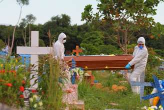 Operários com roupas de proteção realizam enterro em Manaus, no Amazonas
