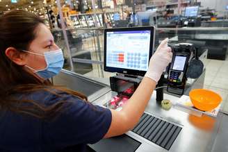 Uma mulher, que trabalha como caixa em um supermercado, limpa os instrumentos de trabalho em Bad Honnef, nas proximidades de Bonn, na Alemanha. 27/04/2020. REUTERS/ Wolfgang Rattay. 